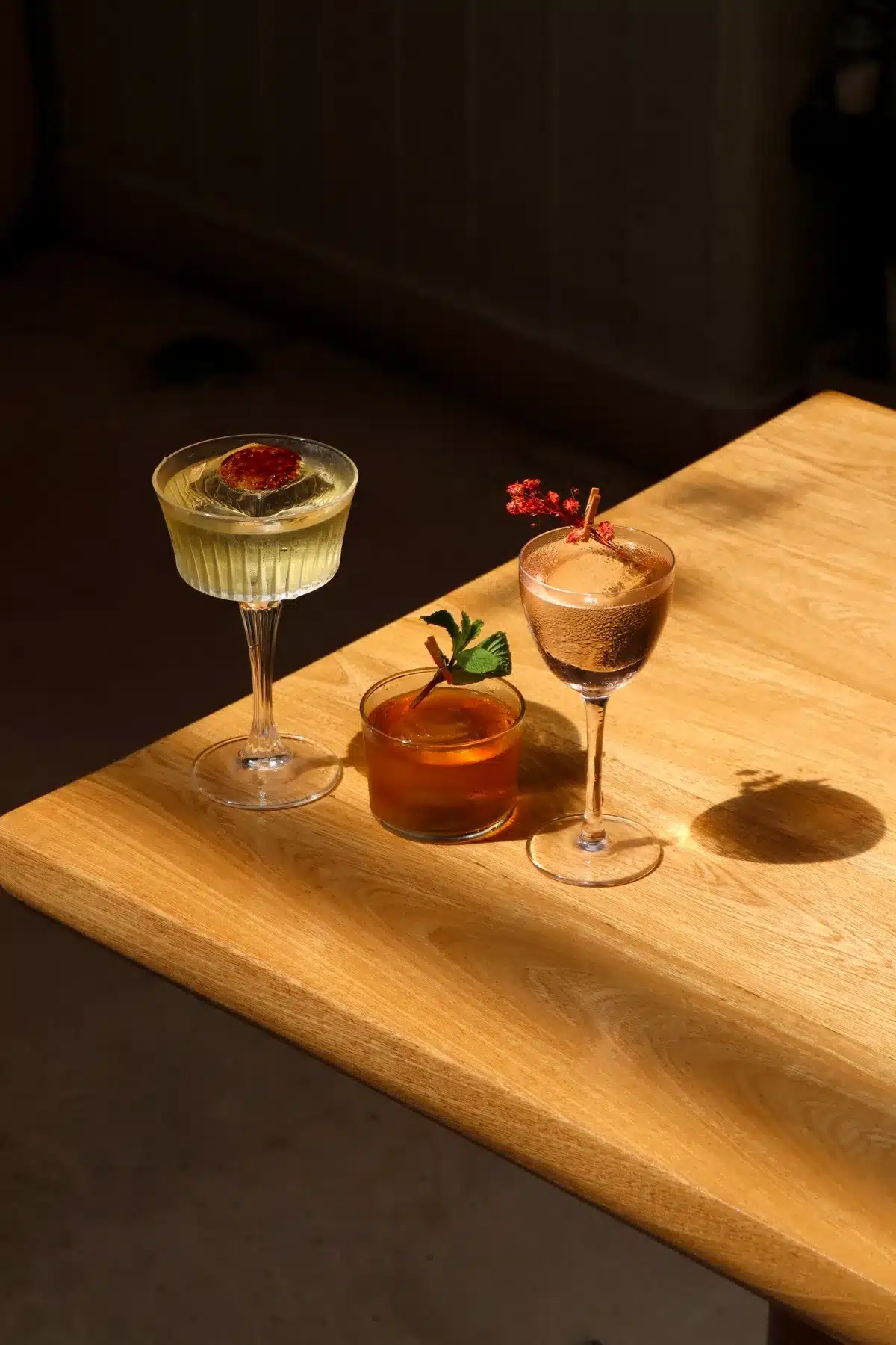 Three house cocktails on a wooden table